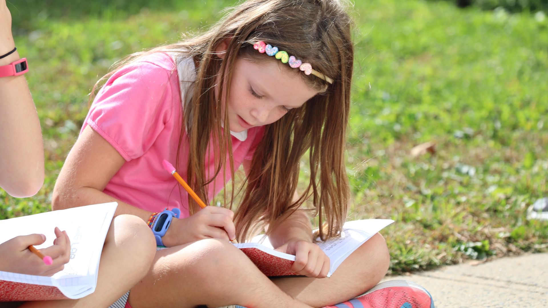 Photo of stuent sat outside writing in note book